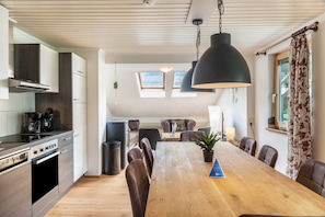 A modern kitchen with a dining area, wooden flooring, and a large table with chairs.