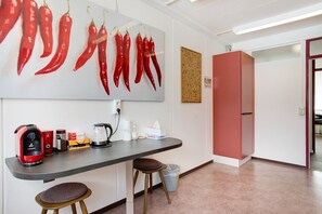 A kitchenette with a coffee maker, kettle, and various kitchen items on the counter. - Vacation Home "Commune88 East" with Shared Terrace & Wi-Fi (Friedrichshafen, Germany)