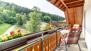 Un balcon avec une balustrade en bois, une table et deux chaises.