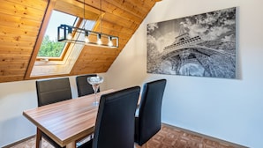 Un espace repas doté d’un plafond en bois, d’une lucarne, d’un lustre et d’un tableau représentant la Tour Eiffel.
