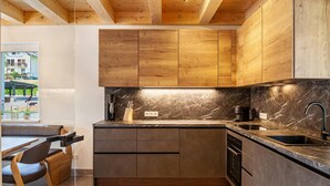 A modern kitchen with wooden cabinets, a marble countertop, and built-in appliances.
