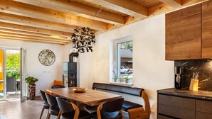 A modern kitchen with wooden cabinets, a dining table with chairs, a bench, and a view of the outside.
