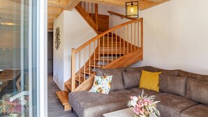 A modern interior with a wooden staircase, a brown sofa, and a vase with flowers.