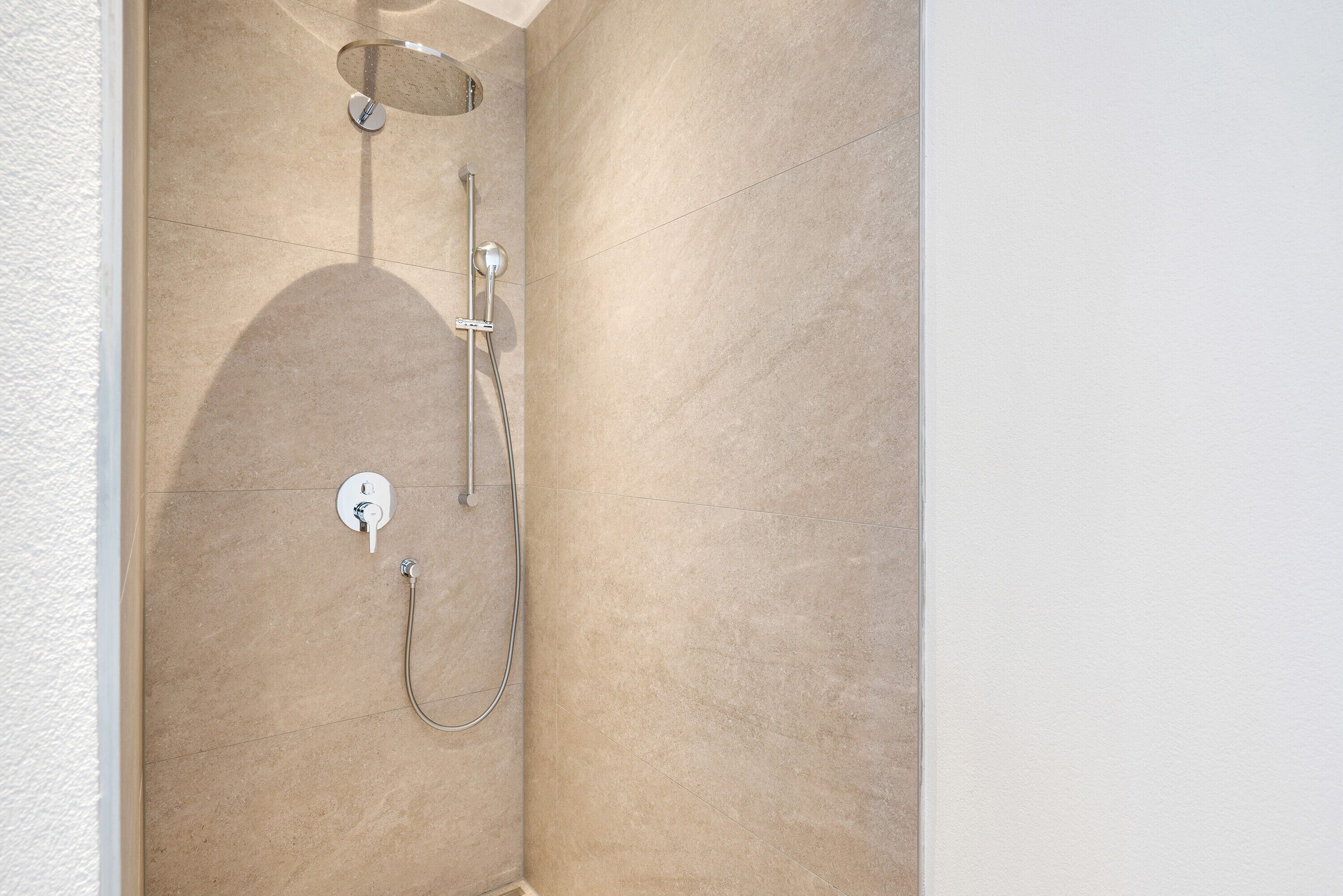 Eine Dusche mit Handbrause und Armaturen an der Wand.