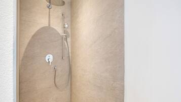 Eine Dusche mit Handbrause und Armaturen an der Wand.