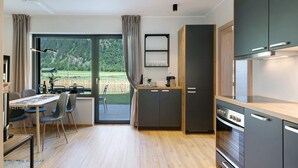 A modern kitchen with a dining area, large windows, and a view of the outdoors. - Sleep in Stubaital: Apartment 'Stackler54 - With Garden', Mountain View, Terrace, Wi-Fi (Neustift im Stubaital)