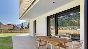 A patio with a wooden table and chairs, a view of a mountain landscape, and a wooden fence. - Sleep in Stubaital: Apartment 'Stackler54 - With Garden', Mountain View, Terrace, Wi-Fi (Neustift im Stubaital)