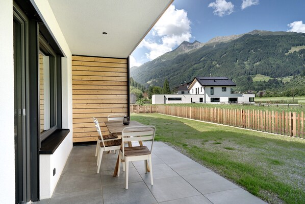 Eine Terrasse mit Tisch und Stühlen, ein Holzzaun und Blick auf die Berge.