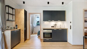 A modern kitchen with a built-in oven, a wooden cabinet, and a black countertop. - Sleep in Stubaital: Apartment 'Stackler54 - With Garden', Mountain View, Terrace, Wi-Fi (Neustift im Stubaital)
