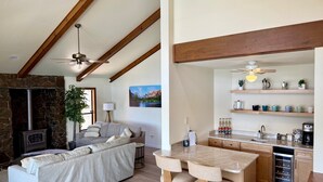 A living room with a stone fireplace, a sofa, and a dining area with a bar.