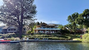 A multi-story building with balconies, a dock with boats, and a calm water body.