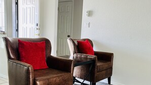 Two brown leather armchairs with red cushions in a room with white walls and wooden flooring. - Casa Feliz is minutes from Colorado River, Oatman, Casinos, Laughlin. (Fort Mohave)