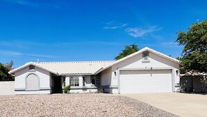 A two-story house with a garage, a driveway, and a clear blue sky. - Casa Feliz is minutes from Colorado River, Oatman, Casinos, Laughlin. (Fort Mohave)