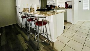 A kitchen with a central island, bar stools, and a dining table. - Casa Feliz is minutes from Colorado River, Oatman, Casinos, Laughlin. (Fort Mohave)
