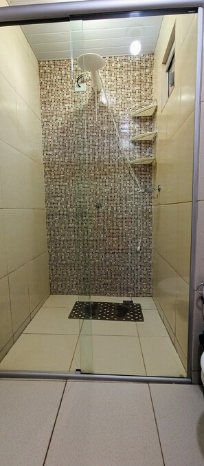 A glass-enclosed shower stall with a tiled mosaic wall, a handheld showerhead, and a handheld shower attachment. - Casa Completa & Confortável (Foz do Iguaçu)