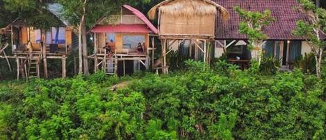 Un conjunto de construcciones rústicas de madera con techos de paja, rodeado de vegetación densa.