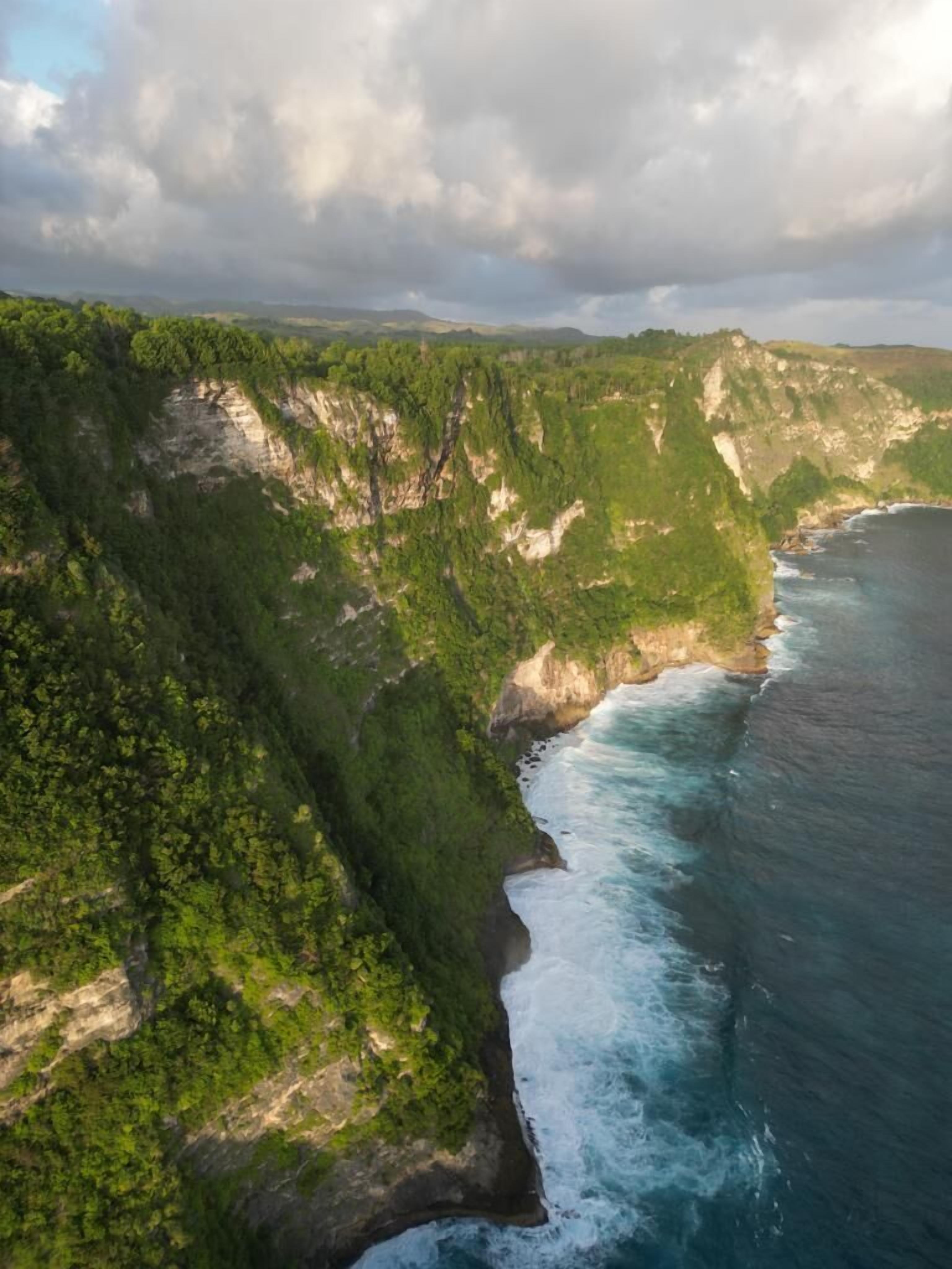 A coastal cliff with a rugged coastline and dense greenery.
