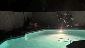 Uma piscina octogonal com borda azulejada e uma mangueira visível na água.