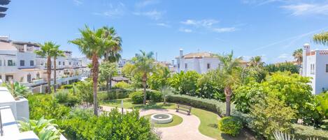 Un patio con palmeras, un jardín circular y edificios blancos.