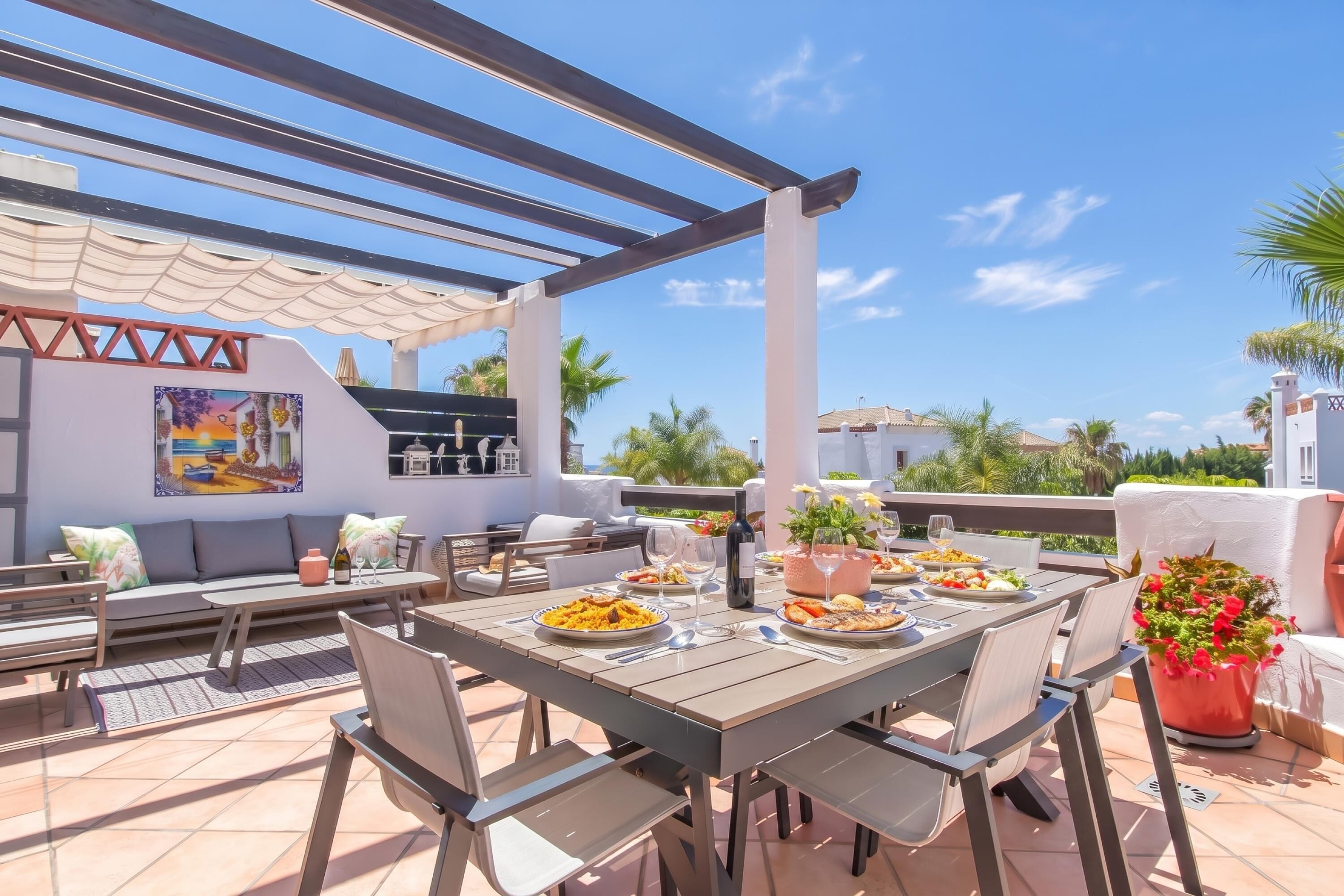 Eine Terrasse im Freien mit einem Esstisch, gedeckt für eine Mahlzeit, umgeben von Stühlen und einer Couch.