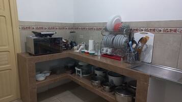 Eine Küche mit Mikrowelle, Mixer, Geschirrgestell und verschiedenen Küchenutensilien.