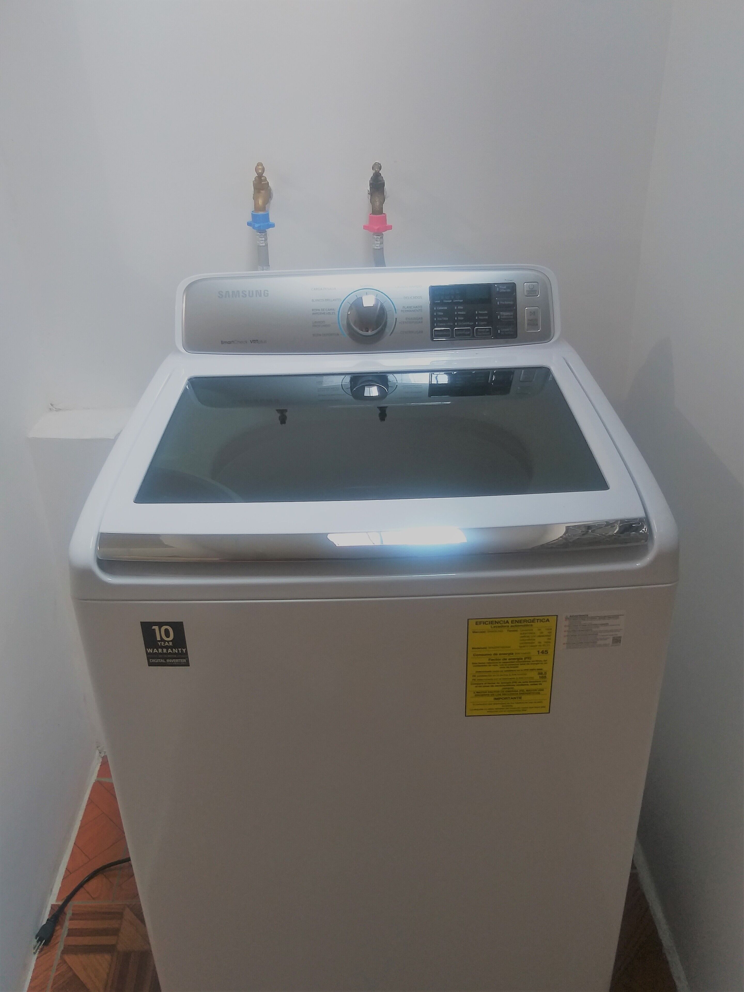 A front view of a Samsung Smart Washer with a 10-year warranty sticker, a digital display, and a control panel.