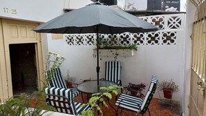 Un espace patio aménagé avec une table et des chaises, un mur décoratif et des plantes en pot.