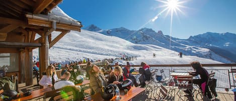 A wooden deck with tables and chairs overlooking a snowy mountain landscape.