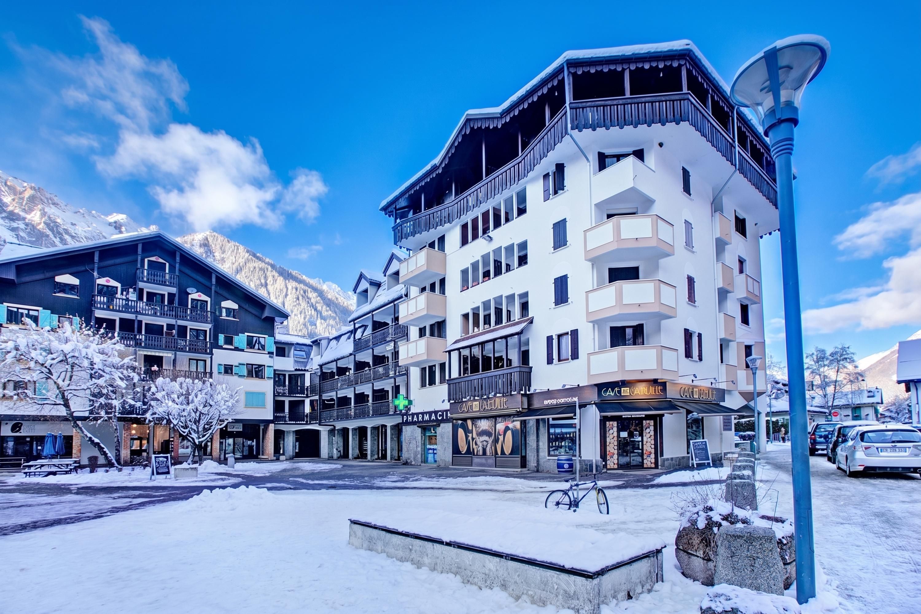 A multi-story hotel with balconies, a pharmacy, and a café.