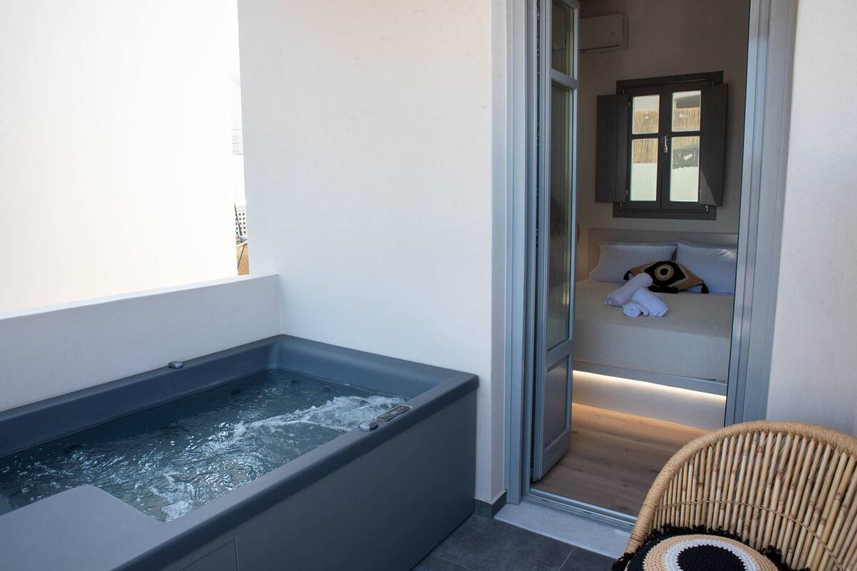 A spa area with a hot tub, a wicker chair, and a bed with towels and a teddy bear.