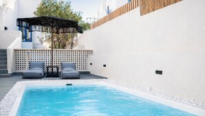 A swimming pool with lounge chairs and a pergola. - Aidani Luxurious Rooms  (Santorini)