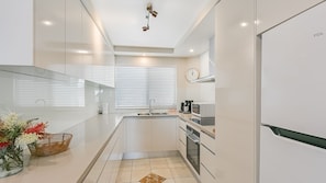 Enjoy cooking in this well-equipped kitchen with an oven, stainless steel sink, and sleek cabinetry.