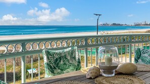 A balcony with a view of the beach and ocean, a candle, and decorative items. - Golden Sea 10 - Absolute Beachfront Bilinga (Bilinga)