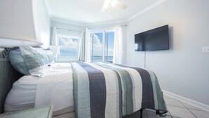 A bedroom with a bed, a ceiling fan, a TV mounted on the wall, and a window with curtains. - Spacious 3 Bedroom/3 Bathroom Beachfront Condo in (Orange Beach)