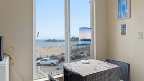 Un balcon avec vue sur la plage, une table avec une lampe et des meubles en osier.