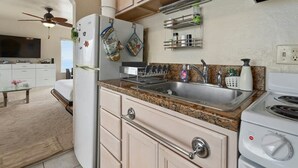 Une cuisine dotée d’un plan de travail en granit, d’un évier en acier inoxydable et d’un four encastré. On y trouve des maniques suspendues et un égouttoir à vaisselle au-dessus de l’évier.