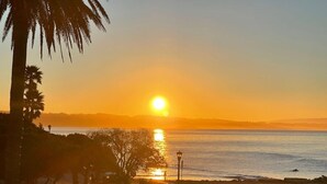 Une scène de plage avec un coucher de soleil, des palmiers et une mer calme.