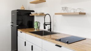 Eine moderne Küche mit einem schwarzen Kühlschrank, einer Holzauskładung, einer Spüle und einem grünen Wasserkocher.