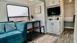 Un espacio habitable compacto con sofá, mesa de comedor, televisor y armario.