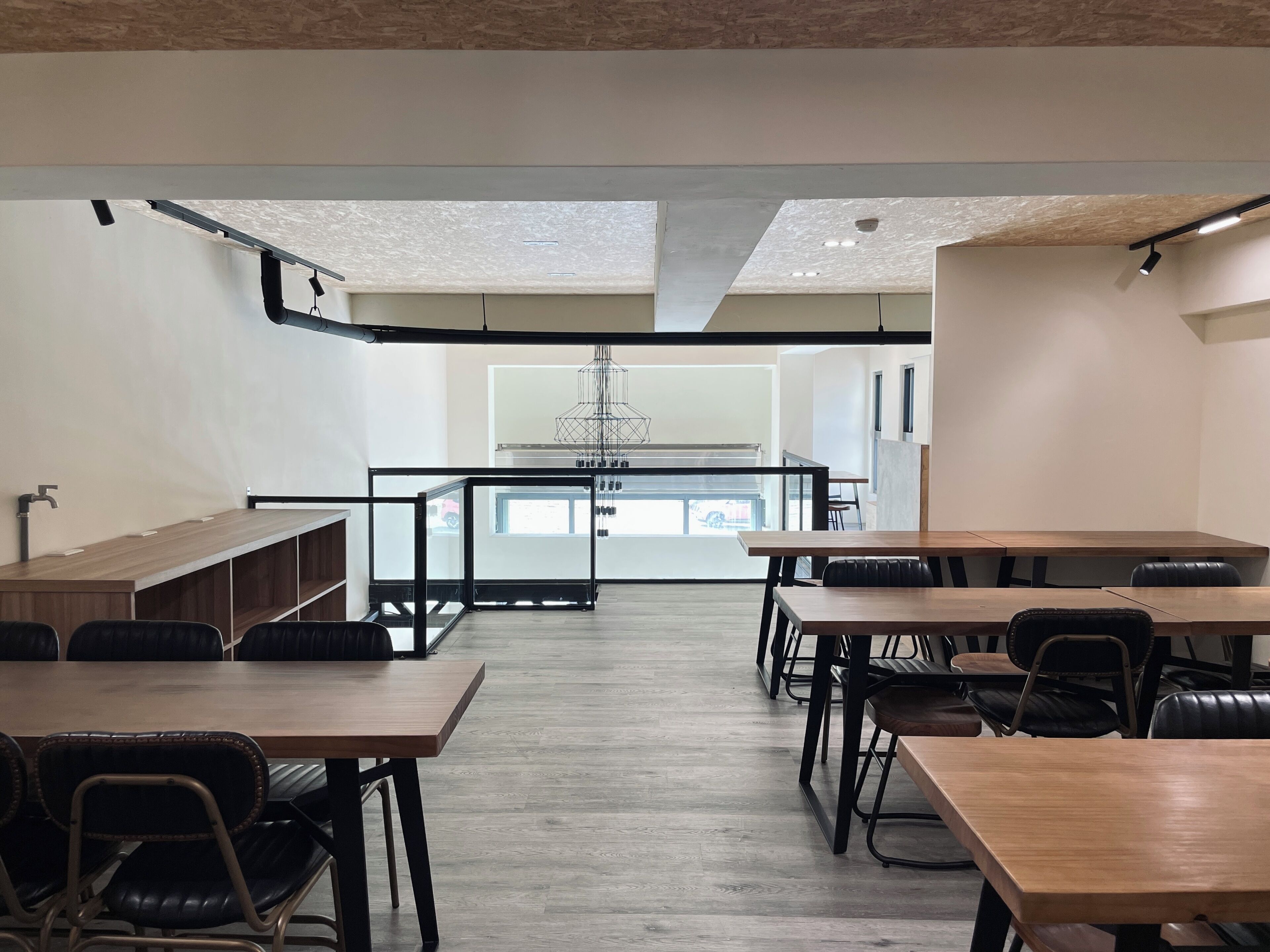 Una sala de conferencias moderna con mesas y sillas de madera, una mesa central con candelabro y vistas al exterior a través de amplios ventanales.