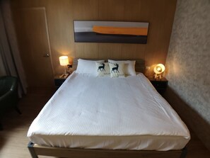 A neatly made bed with white linens, two bedside lamps, and a wall-mounted painting above the bed. - Shigang Hotel (Jinhu)