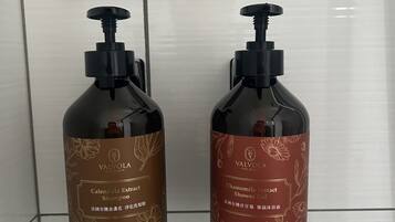 Dos botellas de champú y gel de ducha Valvola, cada una con capacidad de 500 ml, sobre una pared de azulejos.