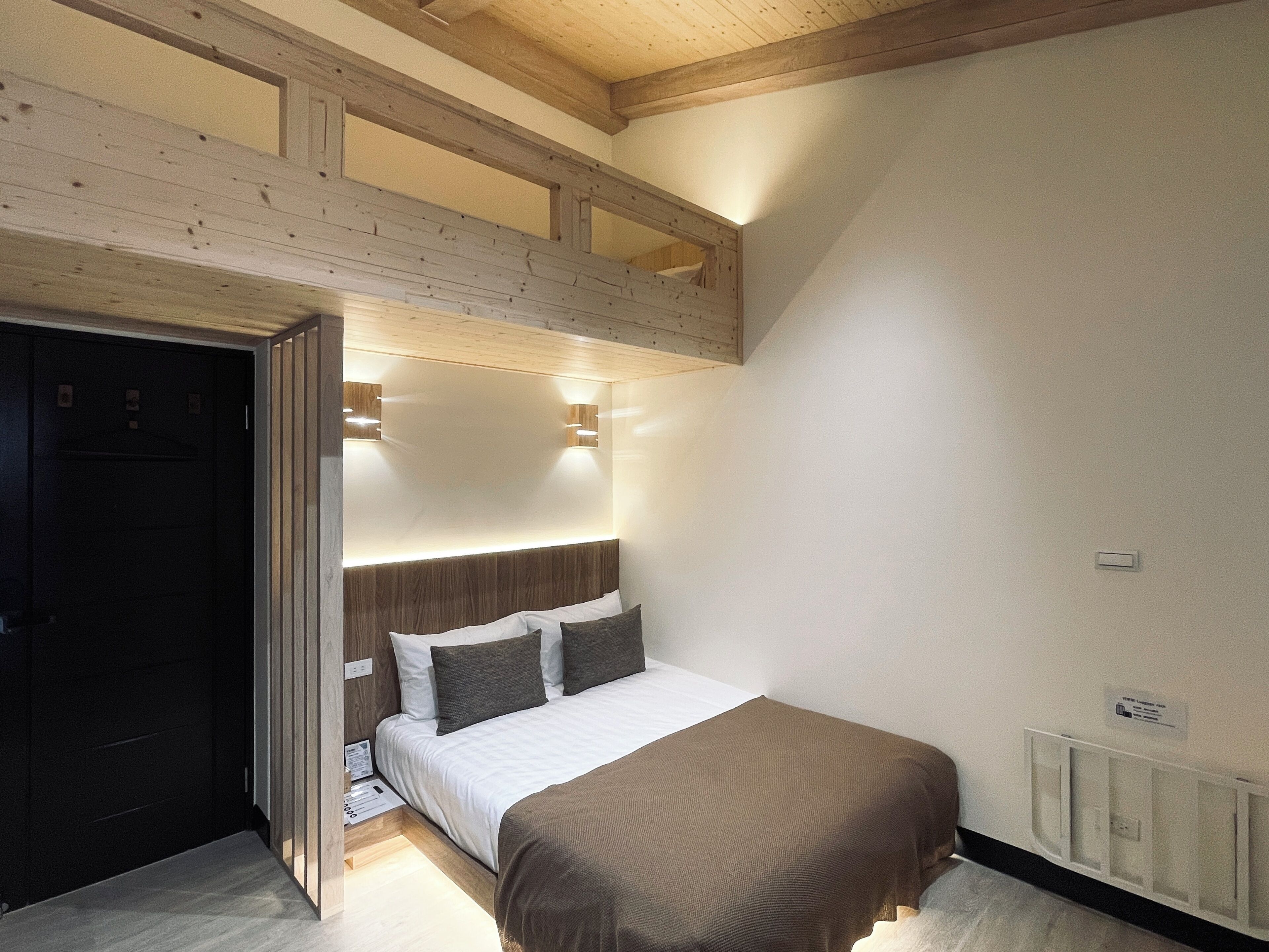 Ein Schlafzimmer mit Bett, Holzbalkendecke, weißer Wand und Heizkörper.
