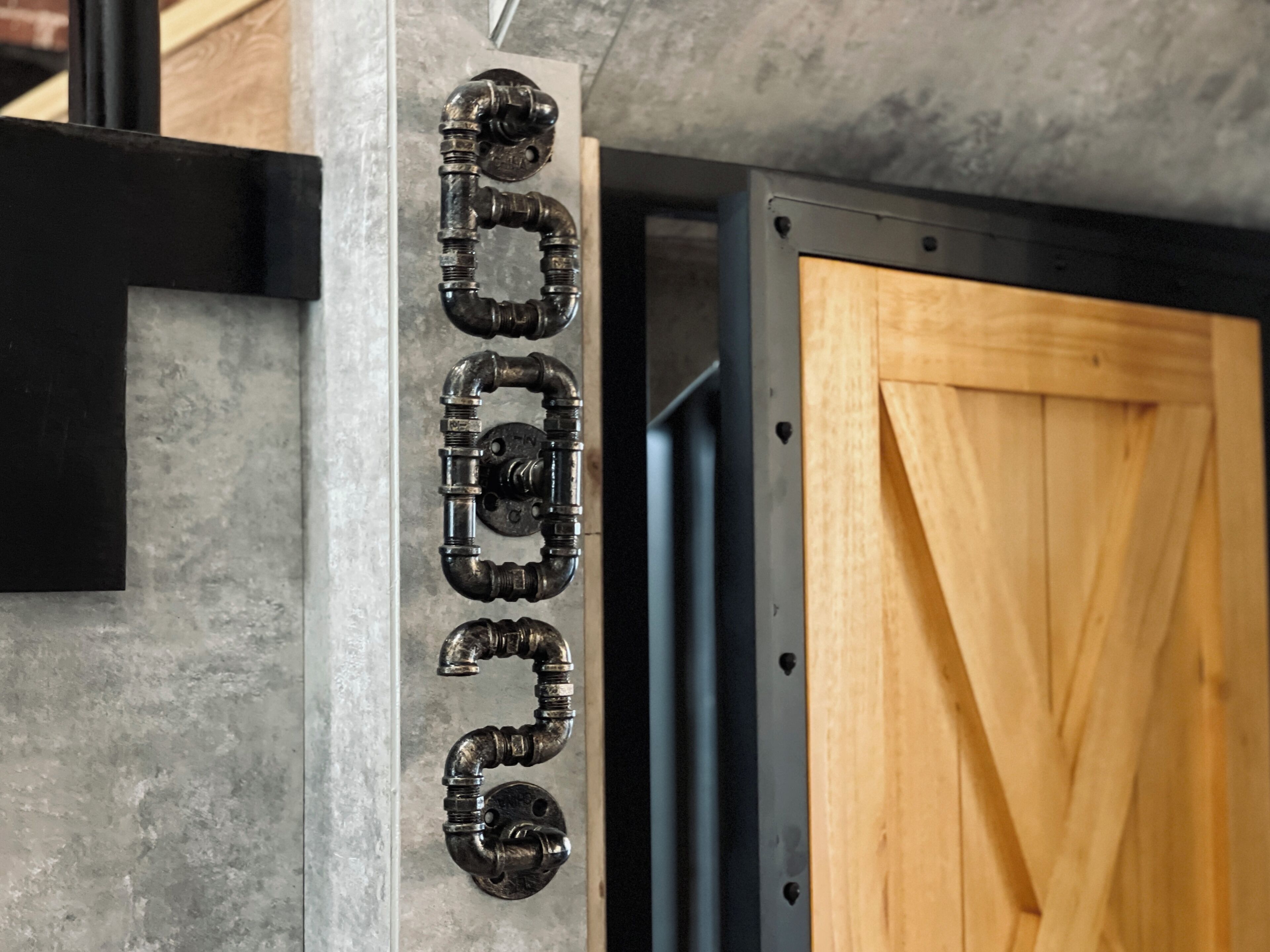 A concrete wall with a metal pipe structure and a wooden door.