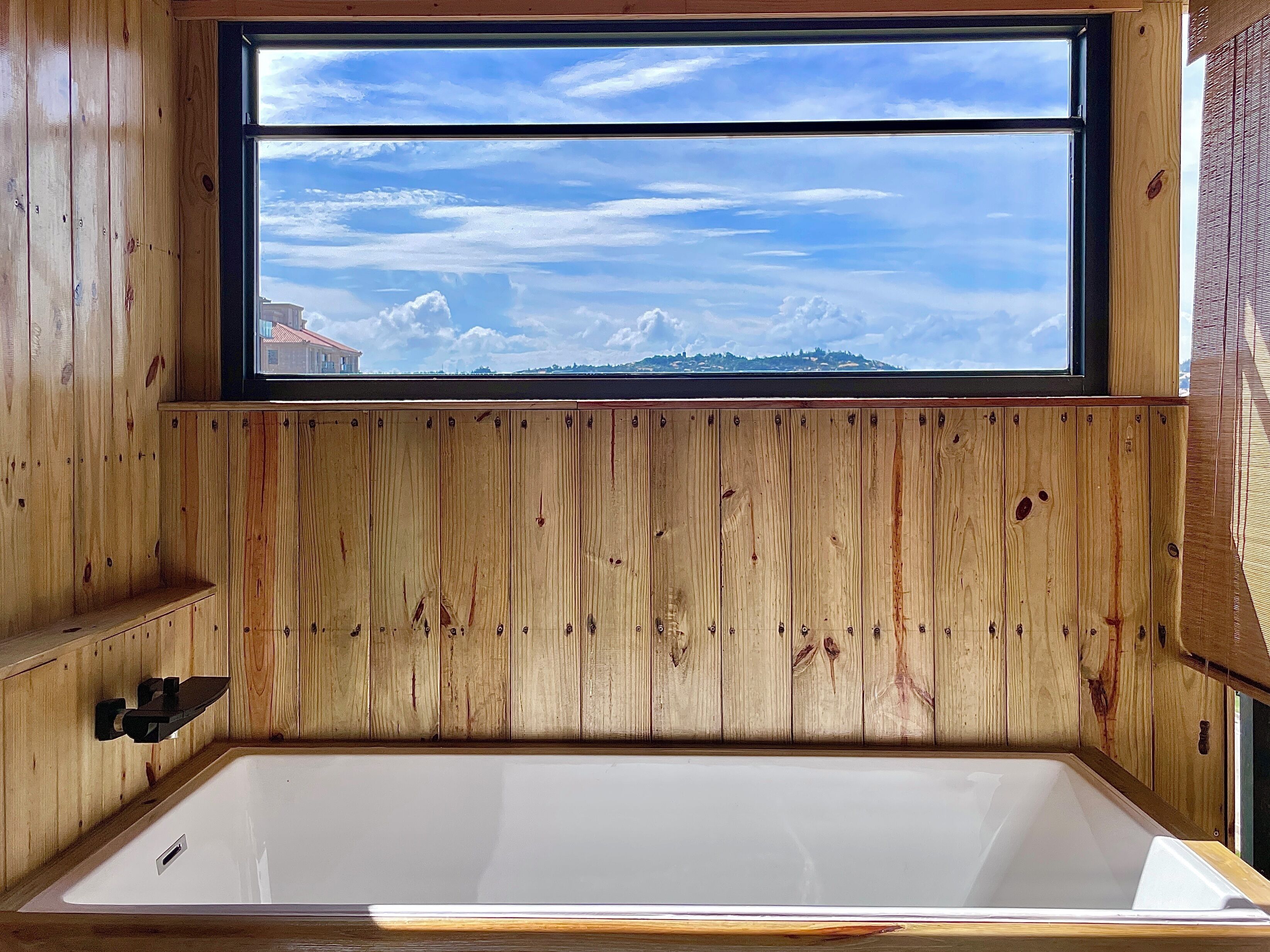 Una cabaña de madera con un ventanal grande, una bañera y un estante de madera.