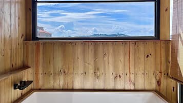 Una cabaña de madera con un ventanal grande, una bañera y un estante de madera.