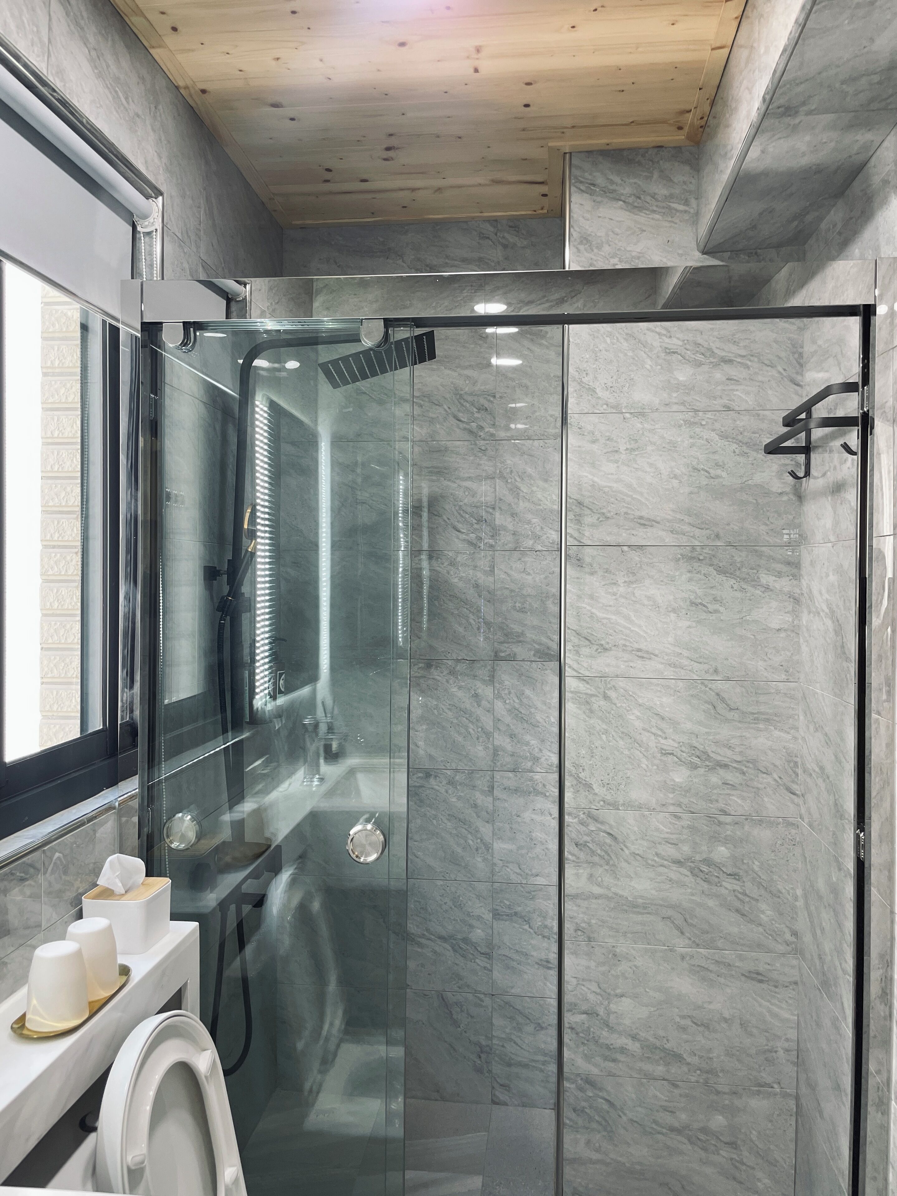 Un baño moderno con ducha envuelta en vidrio, inodoro y lavamanos con espejo.
