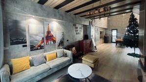 Un salon moderne avec un canapé gris, une table basse ronde et un sapin de Noël.