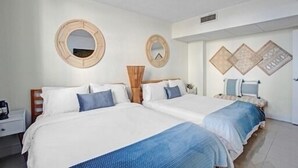 Quarto de hotel com duas camas, uma mesa de cabeceira e um espelho.