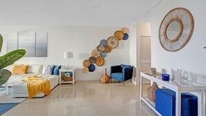 Uma sala de estar moderna com sofá, mesa de centro e um objeto decorativo na parede.